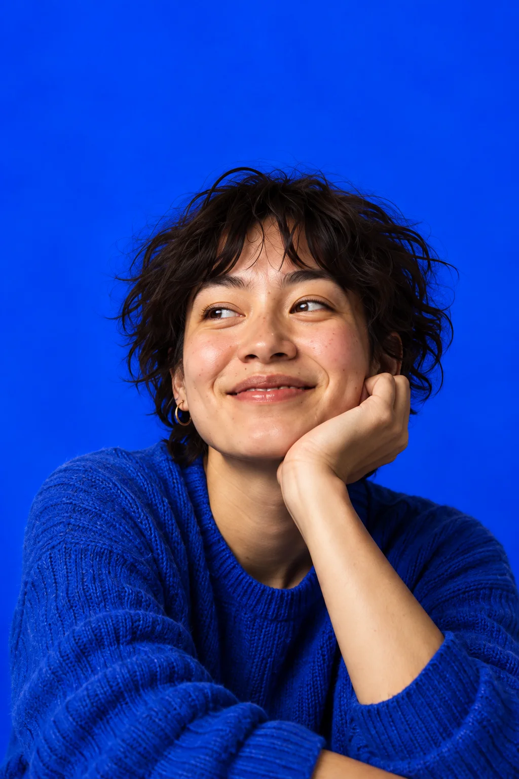 Maya in a blue sweater, resting her chin on her hand.